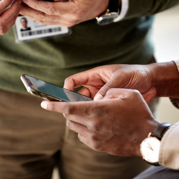 A cropped shot of two people holding smartphones.