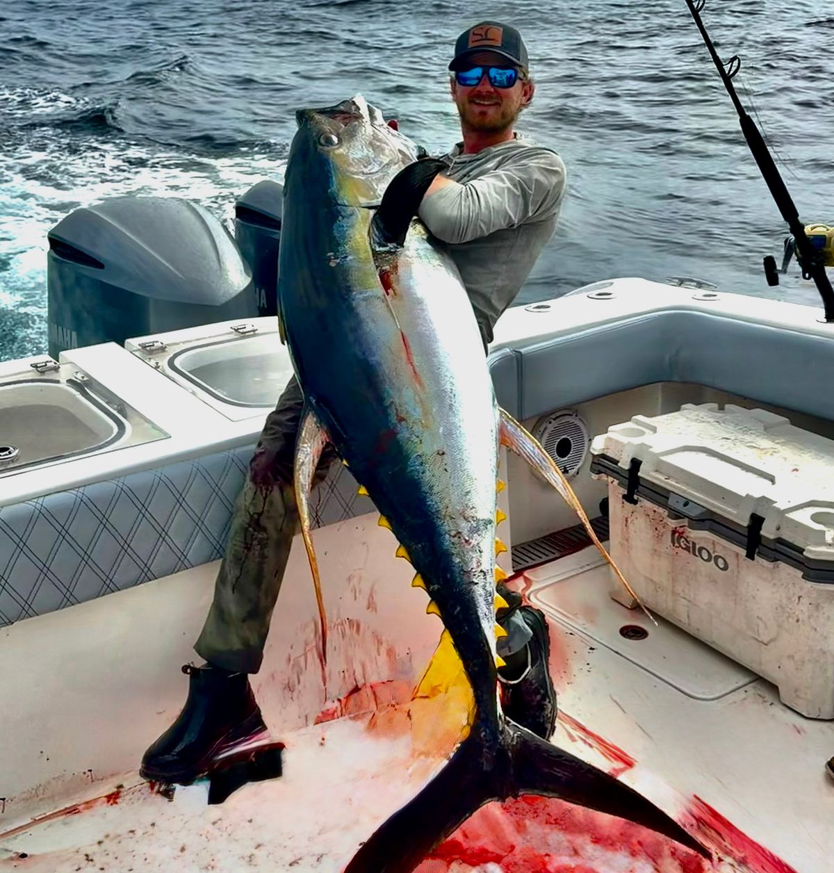 Guy holding up a large Yellowfin Tuna during March fishing