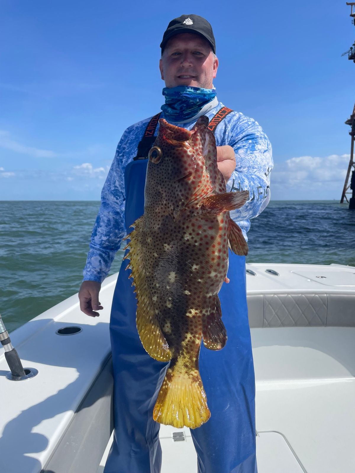 Guy holding up a strawberry grouper during March fishing