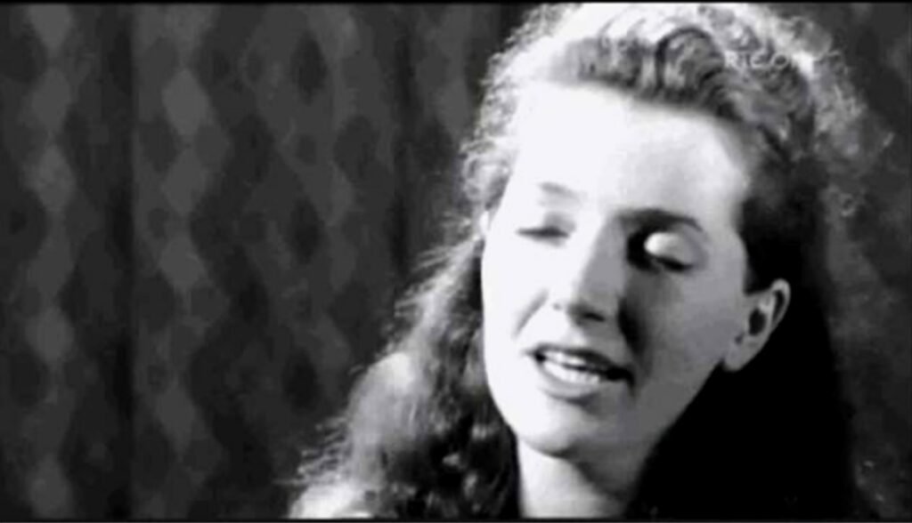 Black and white photo of a woman with long hair singing, her eyes shut