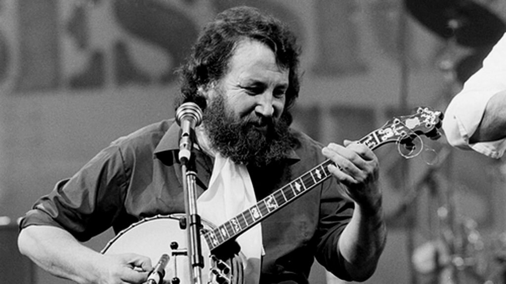 Black and white photo of a man with a beard playing banjo at a microphone