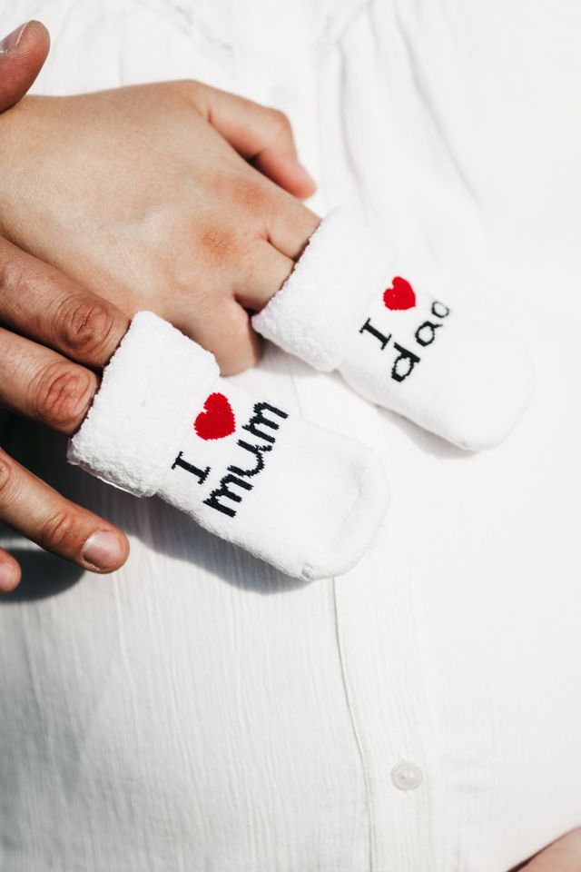 A beautiful depiction of close-up of hands holding baby socks with 'i love mum' and 'i love dad' text., ideal for blogs, ads, or creative design projects.