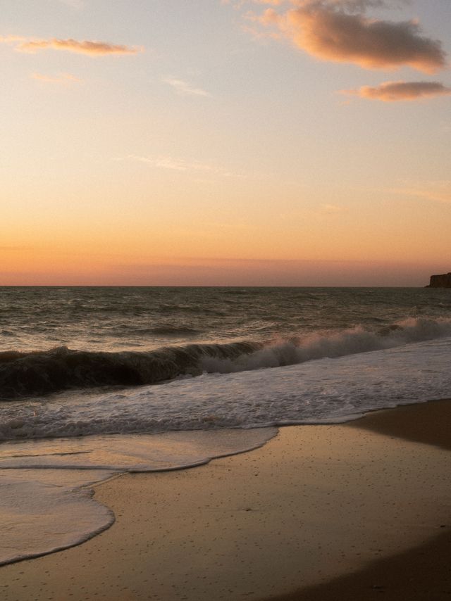 A beautiful depiction of serene beach scene at sunset with calm waves and pastel colors creating a peaceful setting., ideal for blogs, ads, or creative design projects.