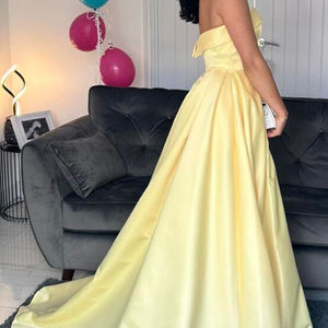 Belle'dress, Soft duchesse satin prom dress in lemon duchesse satin fabric. Fitted boned bodice featuring bandeau neckline. Ballgown skirt with pleats,pockets and train. made to measure in Glasgow