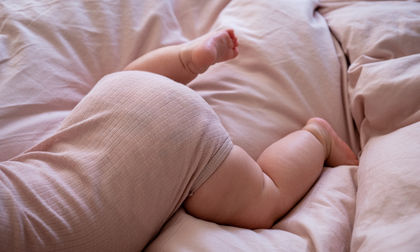 Ein Baby liegt bäuchlings auf einer Bettdecke