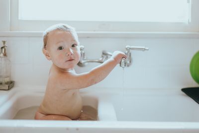 Ein Baby sitzt im Waschbecken und badet