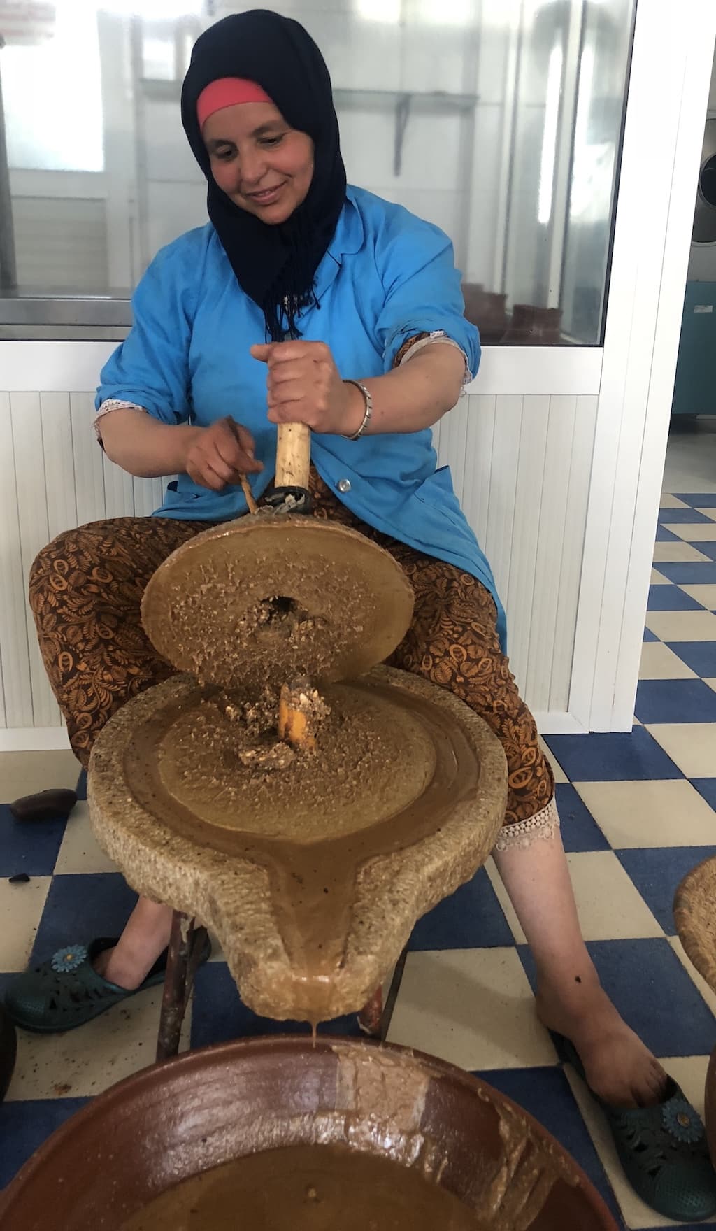 A Moroccan woman grinding argan kernels with a millstone to extract argan oil