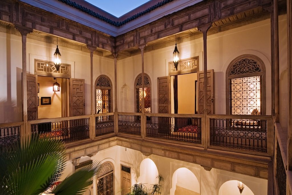 a second-floor balcony above a an interior courtyard with wooden railing and ornamental decoration