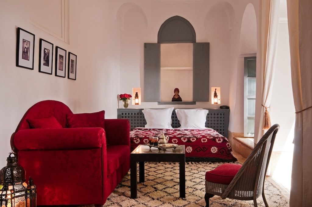 inside of a private room in a riad – a big red velvet sofa, chair and a matrimonial bed with a mint tea served and ready for its occupants