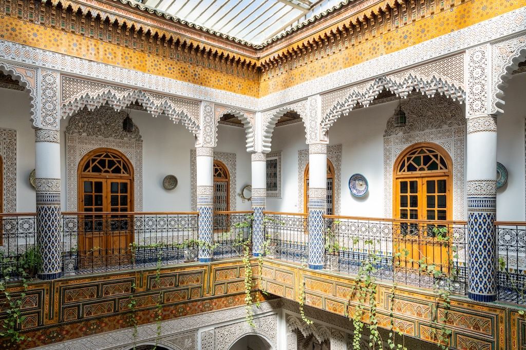 An image displaying Moroccan architecture at its best – a balcony on the second floor of a traditional Moroccan riad with intricate hand-laid tilework and ornamental decoration