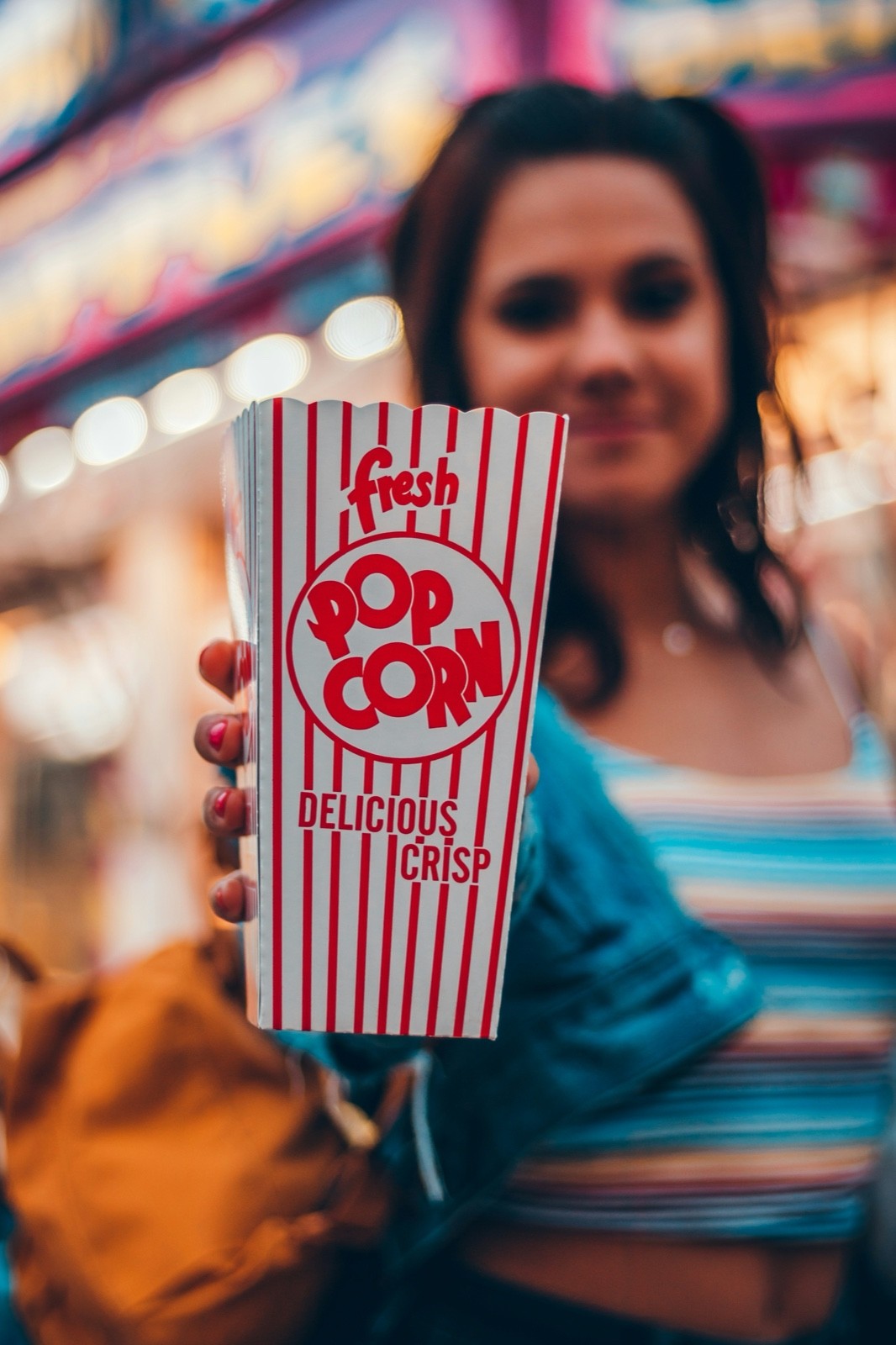 Person holding a striped box of popcorn at an event