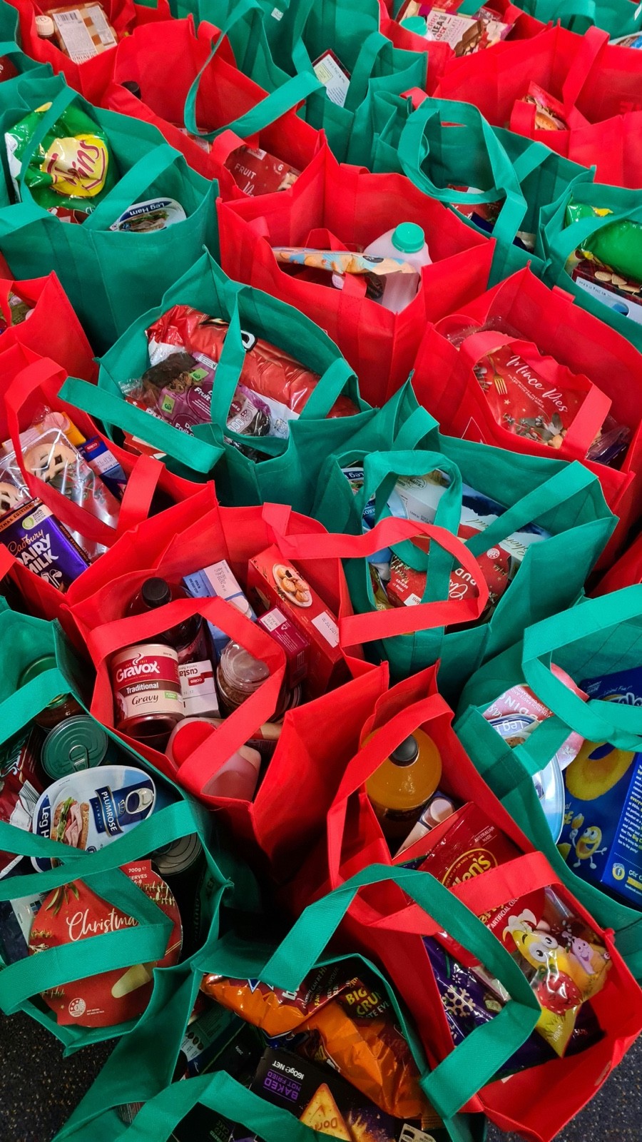 Rows of red and green gift bags filled with donated goods