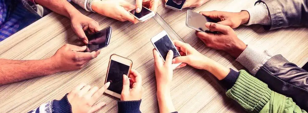 Hands holding smartphones around a table