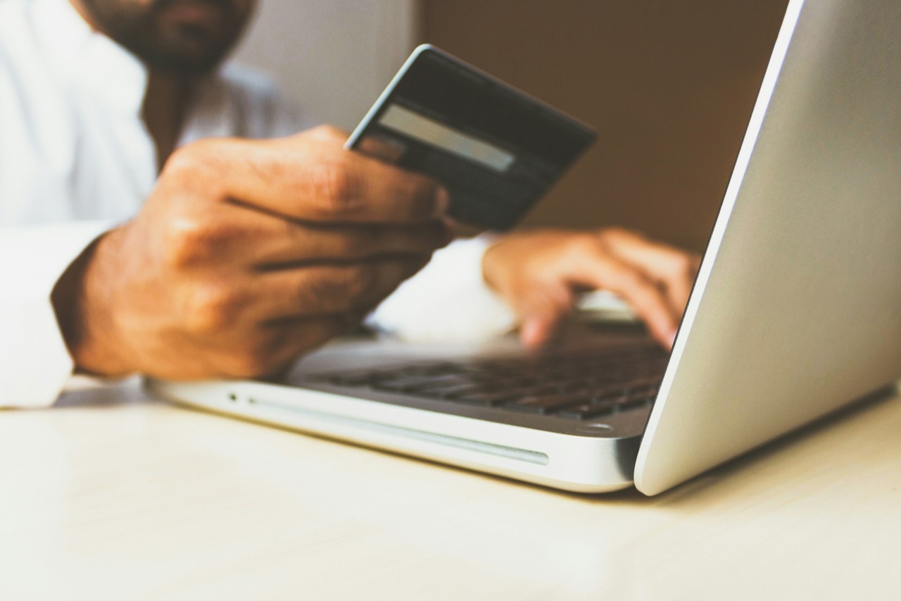 Hands holding a credit card while typing on a laptop