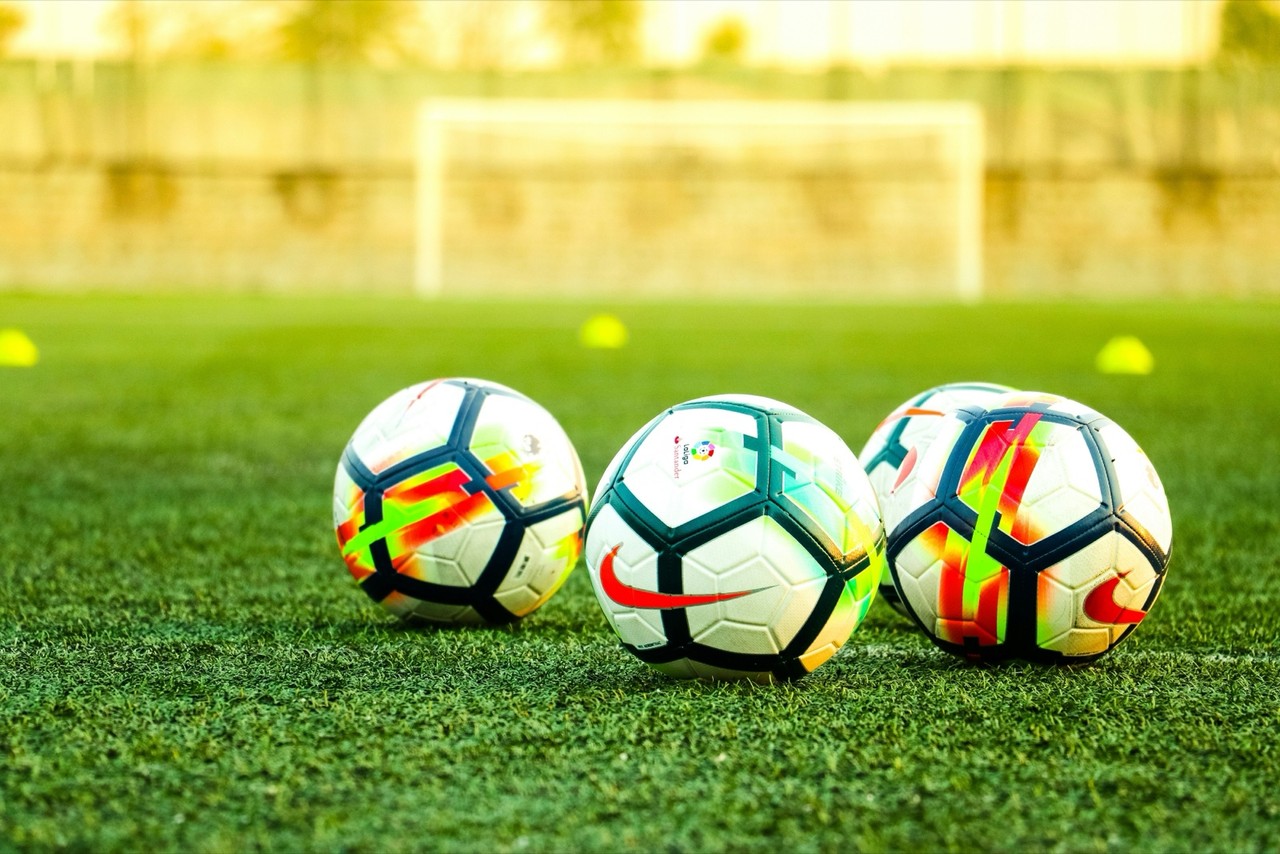 Three soccer balls on a grass field