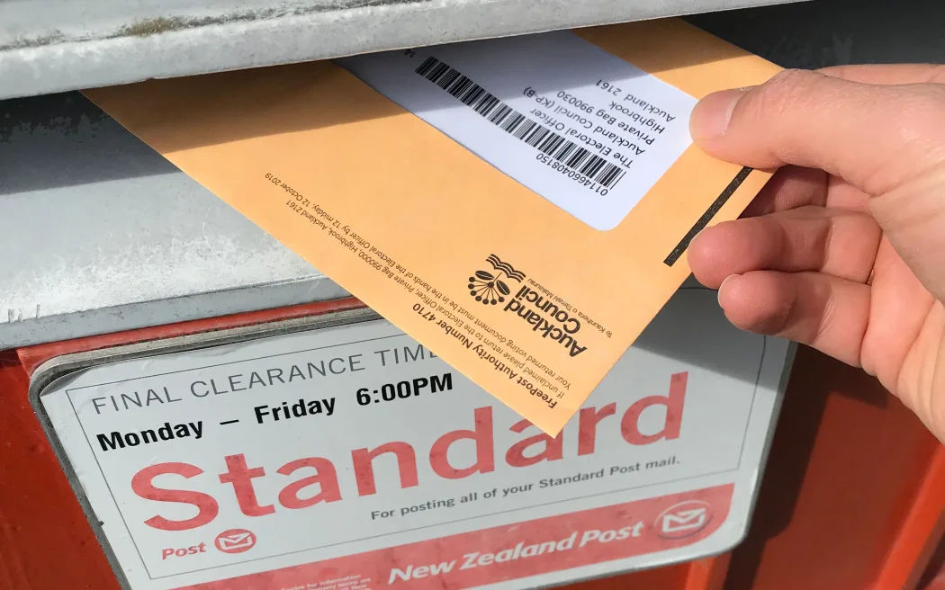 A picture of someone posting a ballot envelope in a post box