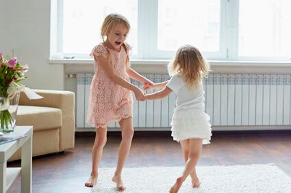 Two Childeren Dancing Around the Floor of Their Living Room