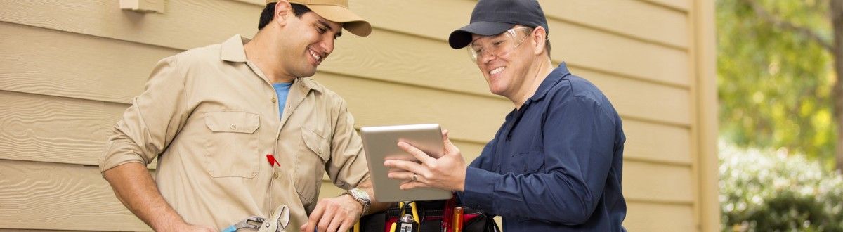 Two Contractors Smiling and Looking Over a Tablet