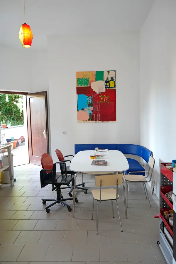 Dining table with blue bench and colorful painting in the kitchen at KOTEKA coworking space Leipzig