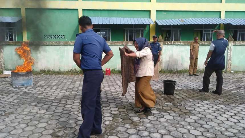 (Pegawai Keurahan Parit Benut, Rika mengikuti praktek memadamkan api menggunakan alat tardisional goni yang dibasahi menggunakan air)