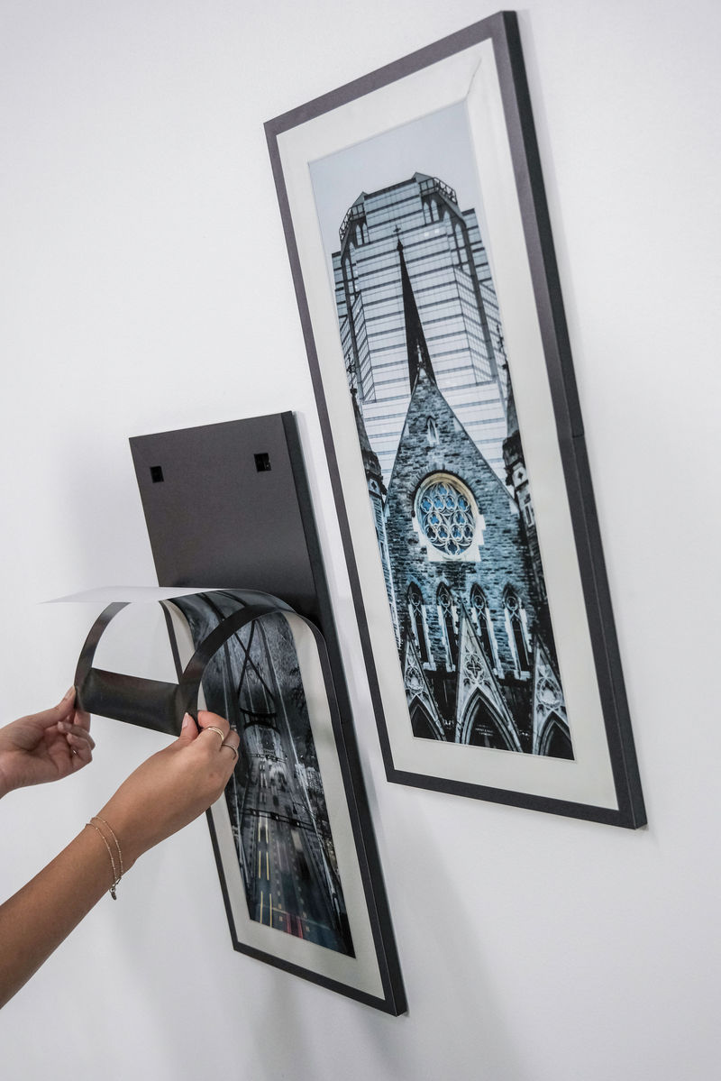 A woman pulling back a magnetic frame revealing an updatable paper insert