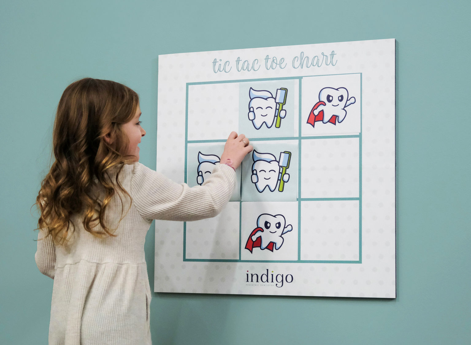 Child interacting with magnetic tic-tac-toe game in a dentist office