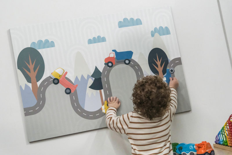 A boy interacting with layers of magnetic cars and trucks on a playful road graphic
