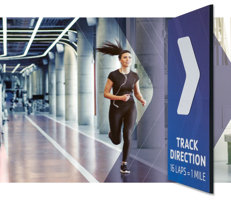 Graphic of a woman running on an indoor track next to a magnetic wall graphic with an adjustable arrow for track direction