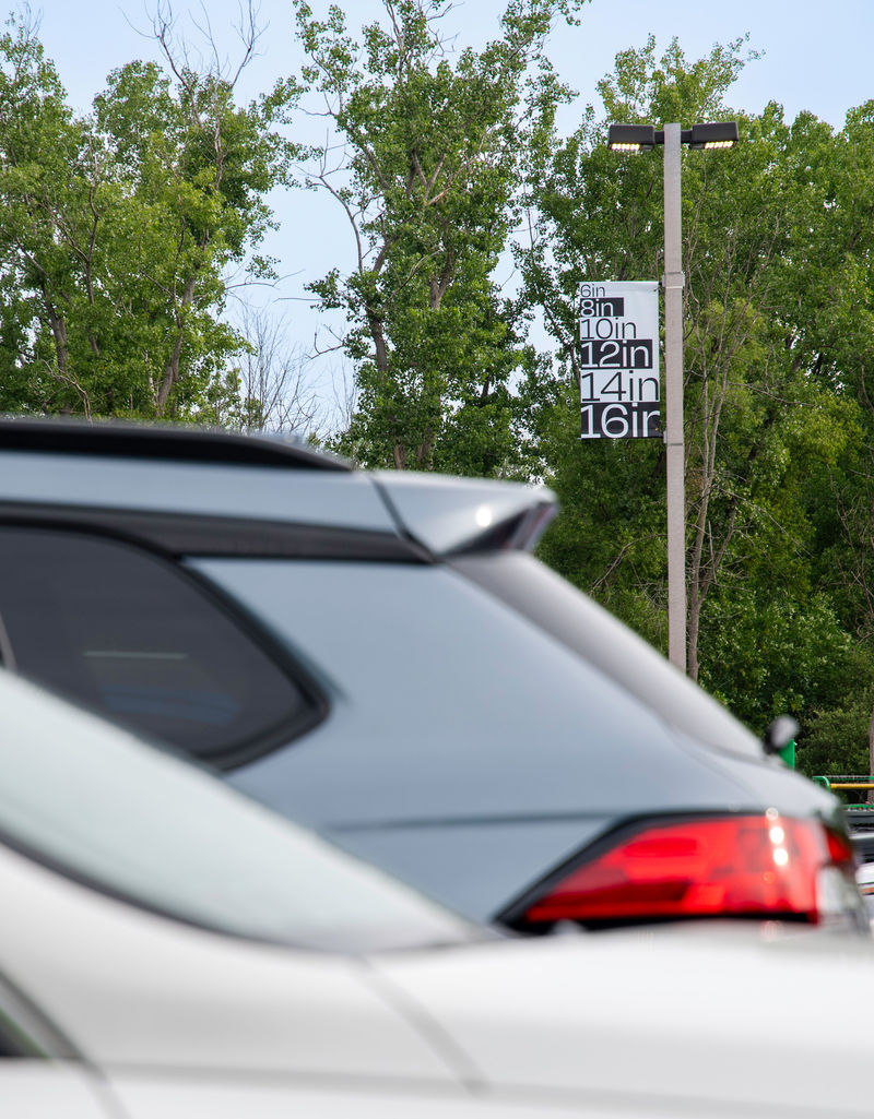 A parking lot with a banner in the distance custom printed with a letter size chart