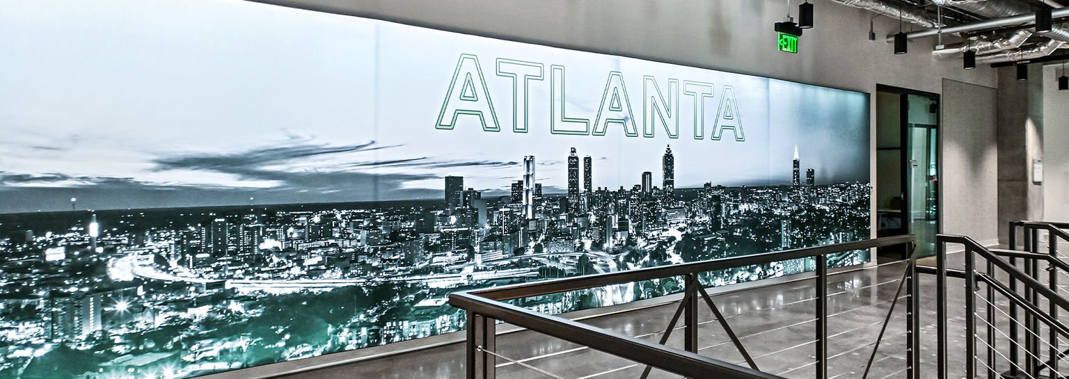 A photo of an wall-to-wall illuminated silicone edge graphic with a custom printed graphic over the Atlanta skyline.
