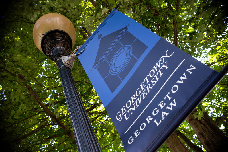 Looking up at a colorful branded pole banner on a college campus.