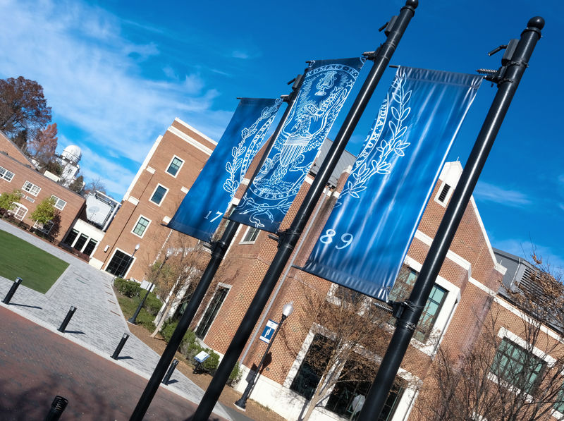 Three exterior banners custom printed and attached to large pole in a Higher Education campus courtyard.