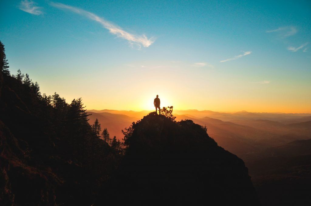 Man watching a sunrise on a mountaintop - Photo by Julentto Photography on Unsplash