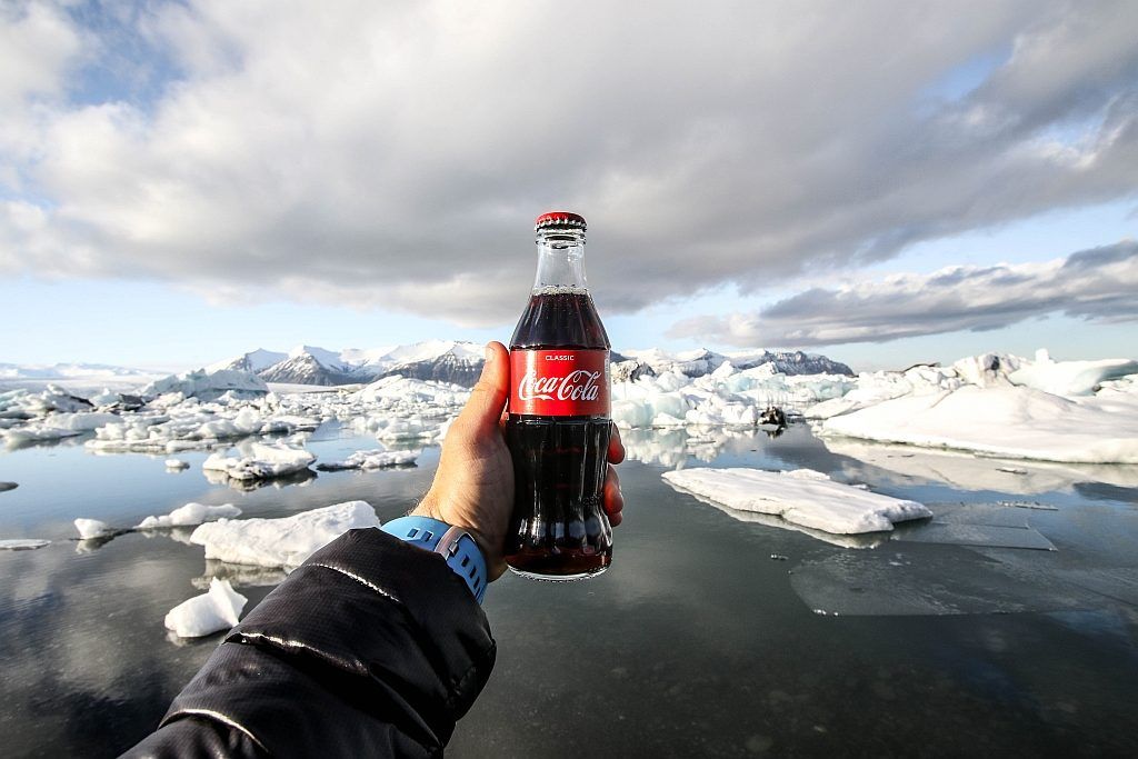 A person holding a bottle of Coke against the background of a glacier
 Photo by Jeremy Bishop on Unsplash 