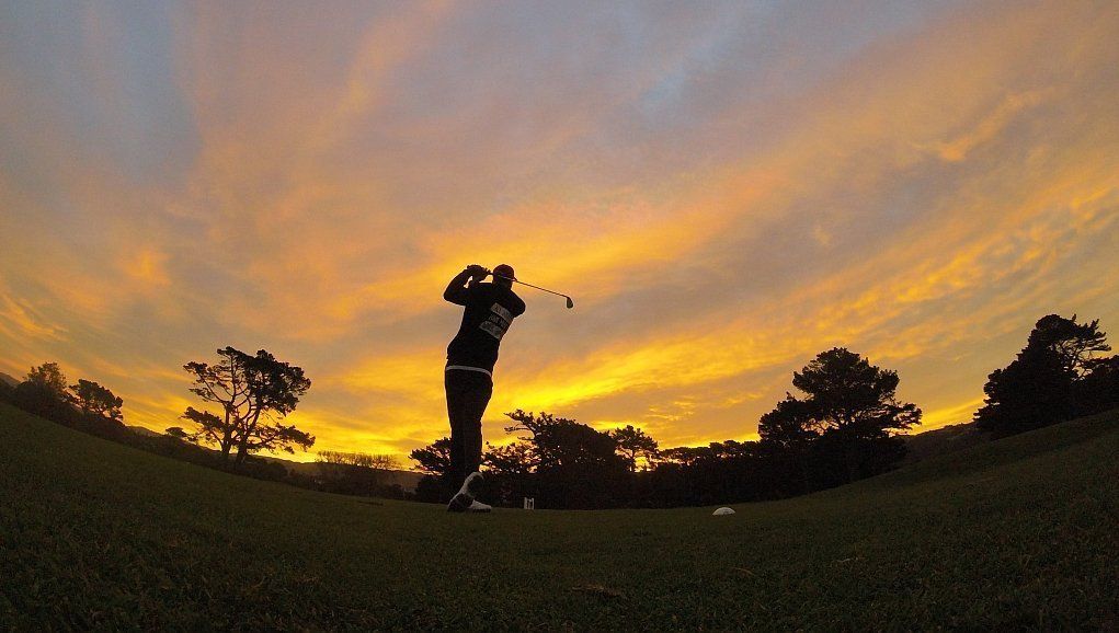 A man tees off into the sunset