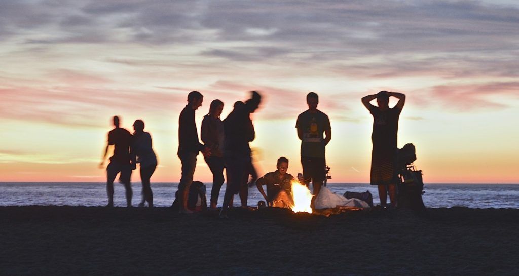 Silhouette of a group of people around a campfire on the beach