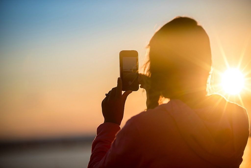 A woman captures a sunset