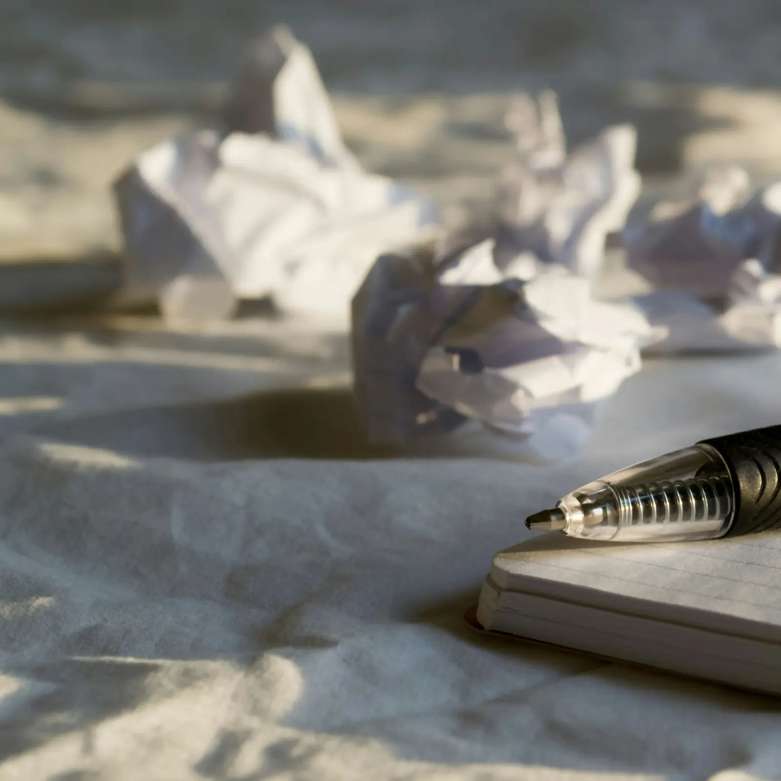 Pen resting on a notebook beside crumpled injury report drafts