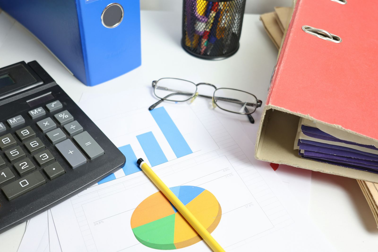 Calculator, folders, and charts on a desk, comparing immigration lawyer costs
