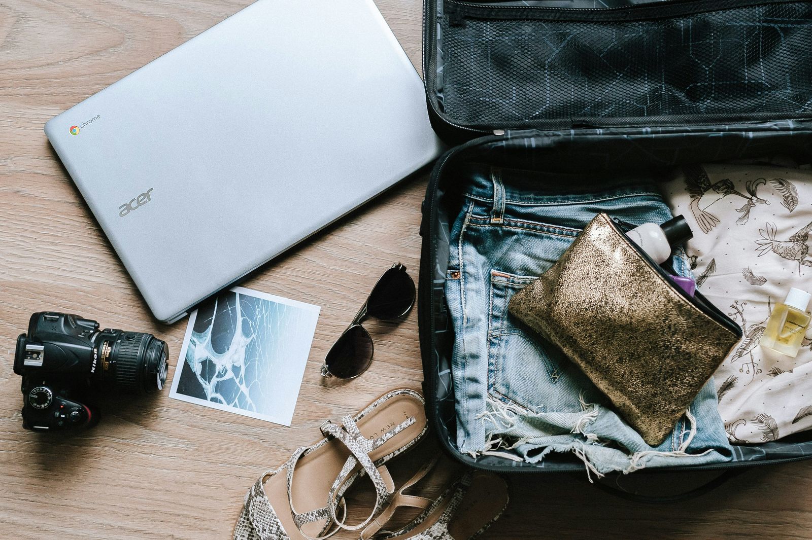Flat lay of a suitcase, laptop, camera, and essentials, preparing for family travel