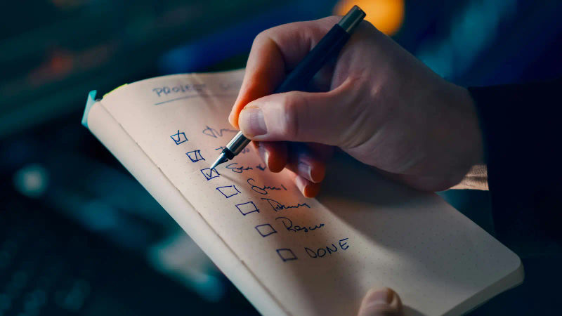 Close-up of a pen marking a checklist in a notebook, organizing travel consent details