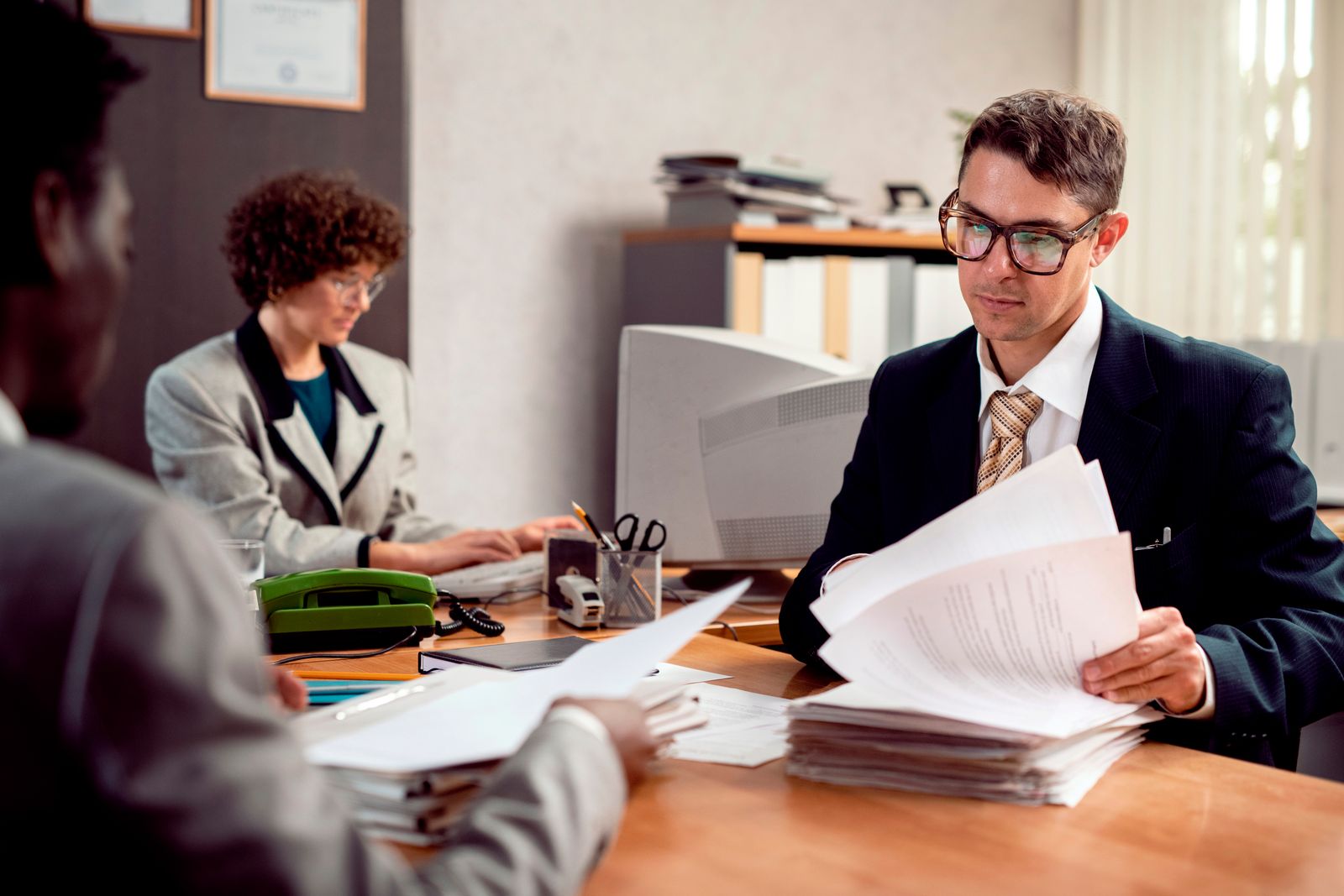Professional lawyer consultation - attorney and client reviewing documents at desk with laptop and legal papers