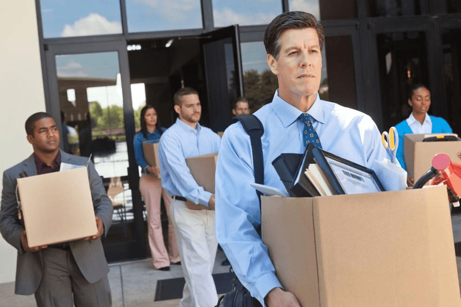 Professionals leaving an office building after a layoff or restructuring event.