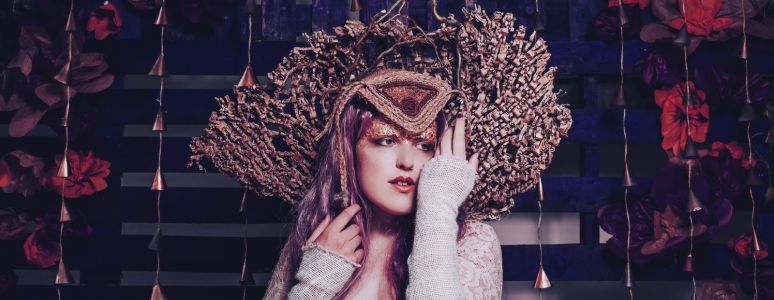 Lucy Ward in an ornate headdress against a dark background 