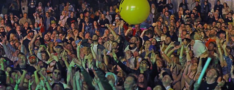 A crowd dances with a beach ball bouncing from person to person.