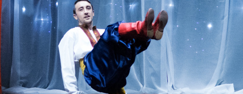 Ukrainian dancer performing a squat kick in traditional clothing