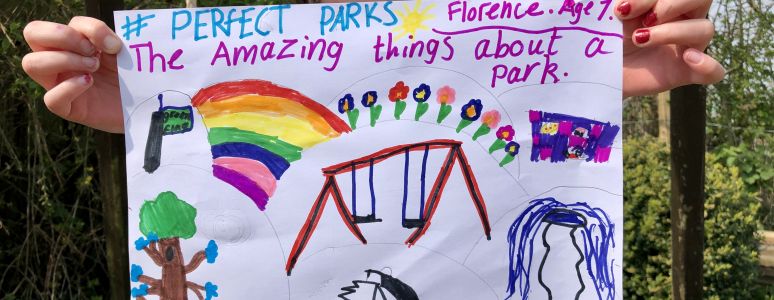 Child holds up brightly coloured painting with flowers, a rainbow, swings, a tree and a fox