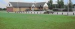 photograph of short green grass field and community building beyond photograph of short green grass field and community building beyond