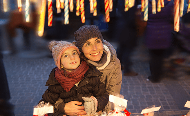 Happy woman and child surrounded by Christmas lights