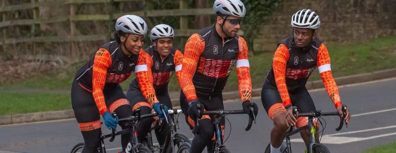 Four cyclists in orange jerseys on bikes outside 